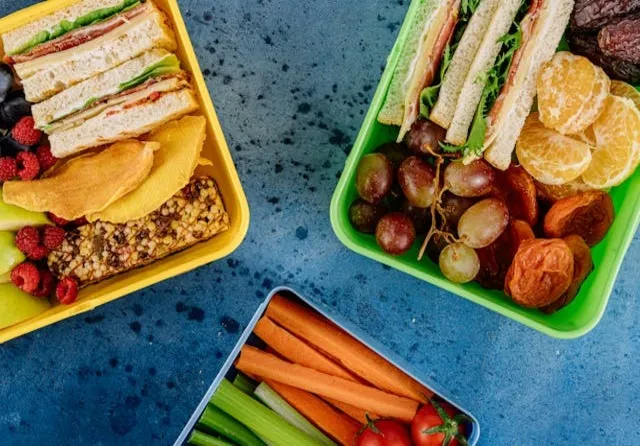 Imagem de legumes, frutas e sanduíches saudáveis em uma bandeja